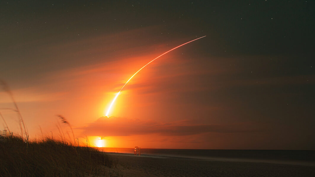 Long exposure night shot of a rocket launch from the beach at night